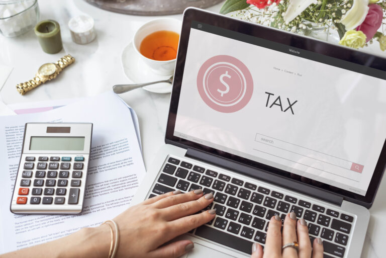 Laptop showing “TAX” with calculator and documents.