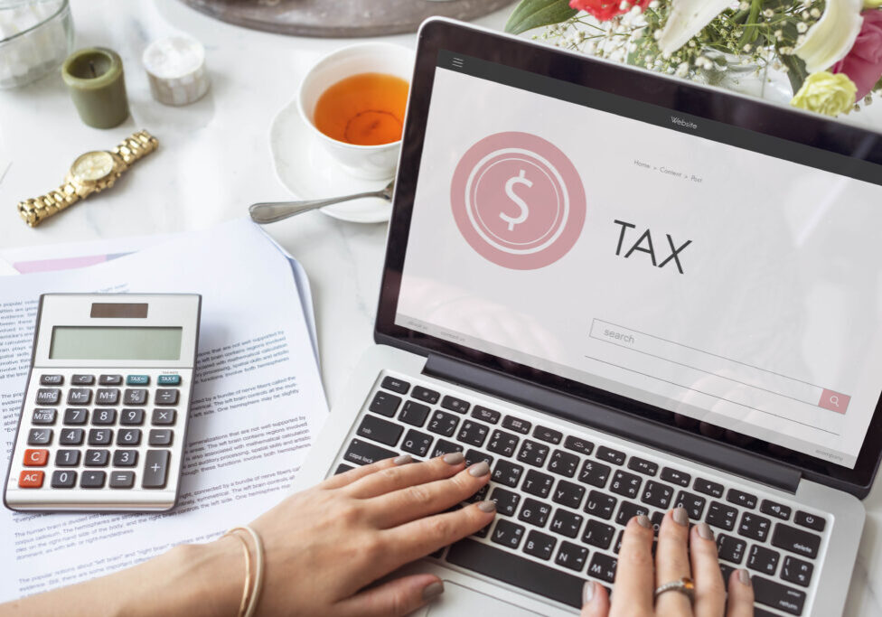 Laptop showing “TAX” with calculator and documents.