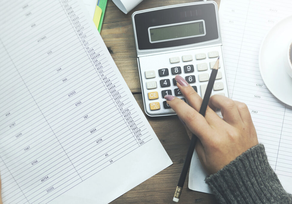 Hand using calculator next to financial spreadsheet representing T3 trust return preparation